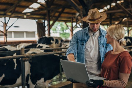 Foto de Una mujer y un vaquero usan la computadora en un granero.. - Imagen libre de derechos