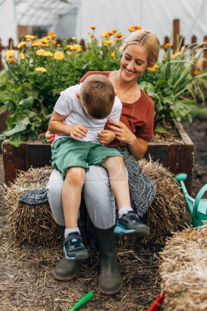 Téléchargez les photos : Belle jeune mère s'amuse avec son fils dans le jardin. - en image libre de droit