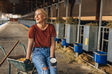 Photo for Beautiful farm girl sitting on a cart in a stable. - Royalty Free Image