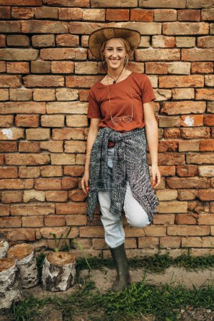 Téléchargez les photos : Cowgirl debout devant un mur de briques. - en image libre de droit