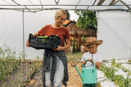 Foto de Caucásico madre e hijo trabajando juntos en el invernadero. - Imagen libre de derechos