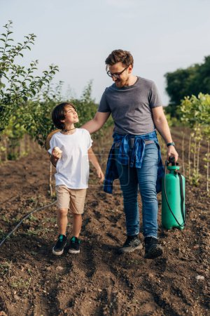 Photo for Father and son walking trough the orchard together. - Royalty Free Image