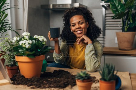 Photo for Portrait of a beautiful florist woman sitting in front of her working surface and drinking coffee. - Royalty Free Image