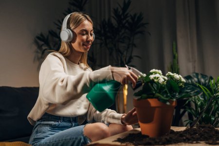Photo for Carefree young woman is spraying her houseplants. - Royalty Free Image