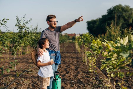 Téléchargez les photos : Père enseigne à son fils le jardinage sur leurs terres agricoles. - en image libre de droit
