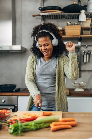 Photo for Biracial woman is having fun singing and coking at the same time. - Royalty Free Image