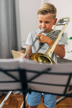Photo for Front view of a determined boy practicing trombone. - Royalty Free Image