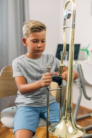 Téléchargez les photos : Un jeune garçon règle son instrument avant la pratique. - en image libre de droit