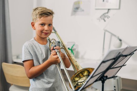 Téléchargez les photos : Un garçon caucasien tient un trombone. - en image libre de droit