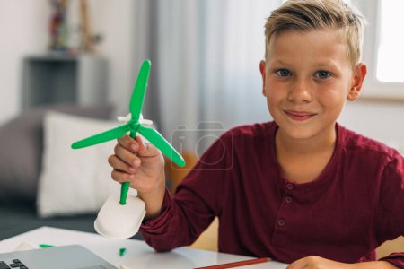 Photo for A young caucasian boy with a windmill model looks at the camera. - Royalty Free Image