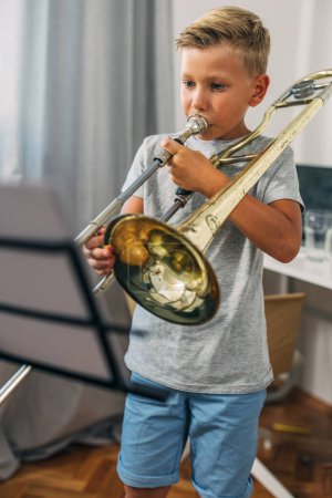 Foto de El chico decidido está practicando trombón en casa.. - Imagen libre de derechos