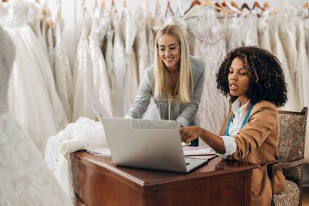 Téléchargez les photos : Tailleur et designer parler à un client dans un appel vidéo sur la demande de robe de mariée. - en image libre de droit