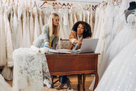 Foto de Vista frontal de dos mujeres en un lugar de trabajo diseñando un nuevo vestido de novia. - Imagen libre de derechos