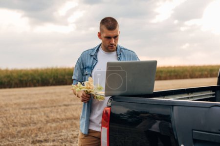 Téléchargez les photos : Farmer utilise son ordinateur portable sur le terrain. - en image libre de droit