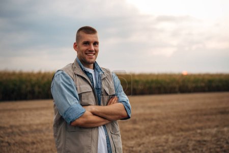 Téléchargez les photos : Portrait d'un fermier heureux debout sur sa terre agricole. - en image libre de droit