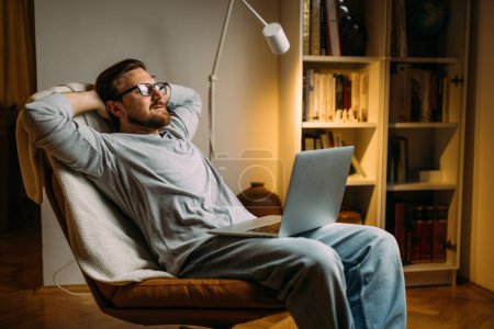 Téléchargez les photos : Un homme se repose avec un ordinateur portable sur ses genoux. - en image libre de droit