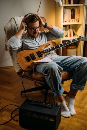 Téléchargez les photos : Musicien met un casque avant de jouer de la guitare électrique. - en image libre de droit