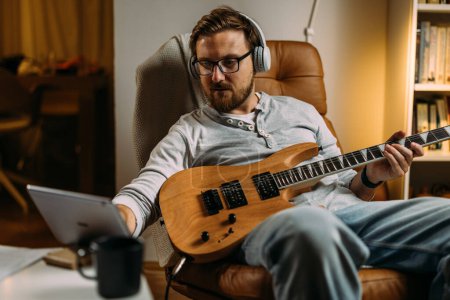 Téléchargez les photos : Guitariste lit des notes sur tablette. - en image libre de droit