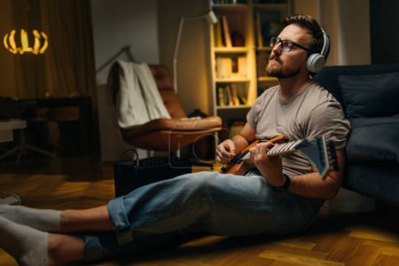 Foto de Hombre caucásico está tocando una guitarra eléctrica conectada al amplificador. - Imagen libre de derechos