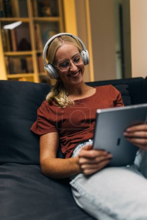 Photo for Happy woman with tablet and headphones at home. - Royalty Free Image