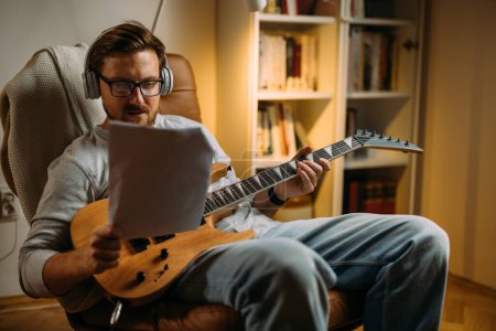 Téléchargez les photos : Homme caucasien avec une guitare électrique lit des notes. - en image libre de droit