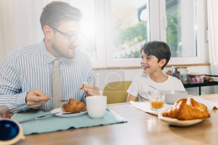 Photo for Father and son eating breakfast together on a sunny day. - Royalty Free Image
