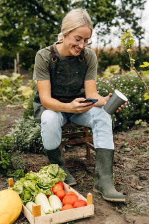 Téléchargez les photos : Jolie jardinière assise sur un tabouret et reposant dans un jardin. - en image libre de droit