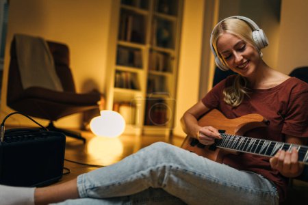Photo for Beautiful Caucasian woman playing an electric guitar at home. - Royalty Free Image
