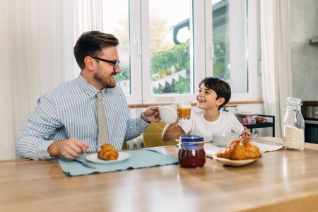 Photo for Working dad is having breakfast with his son. - Royalty Free Image