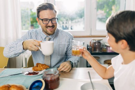 Téléchargez les photos : Père heureux profiter d'avoir le petit déjeuner avec son fils. - en image libre de droit