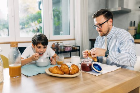 Photo for Boy is eating breakfast with his father before he goes to work. - Royalty Free Image