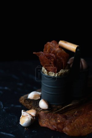 Meat slides, chicken jackers, in an iron box against a dark background. Close up