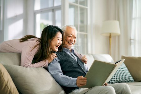 Foto de Asian adult daughter and senior father enjoying conversation and good time at home - Imagen libre de derechos