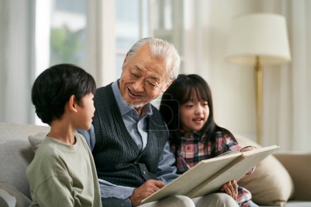 Foto de Senior asian grandfather having a good time with two grandchildren at home - Imagen libre de derechos