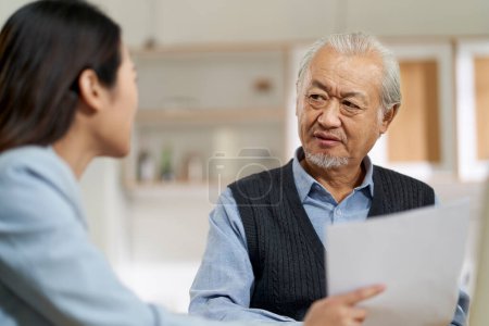 Foto de Senior asian man appears to be confused by and suspicious at a sales person selling financial product - Imagen libre de derechos