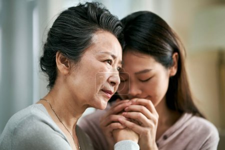 Téléchargez les photos : Young asian adult daughter consoling senior mother living with mental illness - en image libre de droit