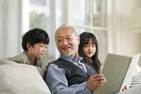 Téléchargez les photos : Asian grandfather having a good time telling story to cute grandson and granddaughter - en image libre de droit