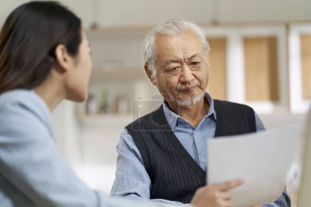 Photo for Senior asian man appears to be confused by and suspicious at a sales person selling financial product - Royalty Free Image
