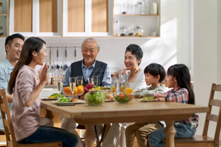 Photo for Multi generational asian family chatting while having meal together at home - Royalty Free Image