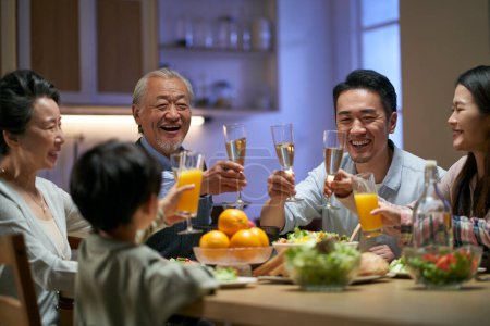 Photo for Three generation asian family gathering at home celebrating holiday having a toast - Royalty Free Image