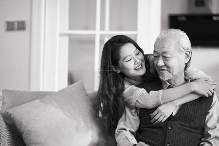 Téléchargez les photos : Asiatique père aîné et adulte fille assis sur canapé dans salon à la maison profiter d'une agréable conversation, noir et blanc - en image libre de droit