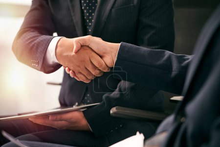 Photo for Close-up shot of two asian business men partners teammates sitting in chairs shaking hands in office - Royalty Free Image