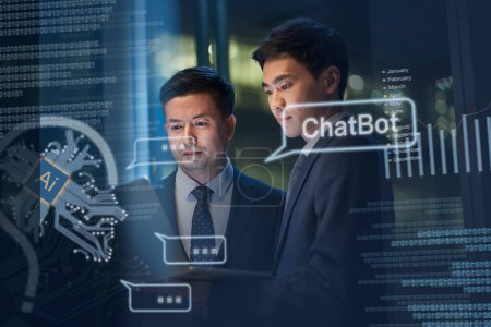 Foto de Dos asiático hombre de negocios trabajando juntos usando ordenador portátil consiguiendo ayuda de AI ChatBot - Imagen libre de derechos