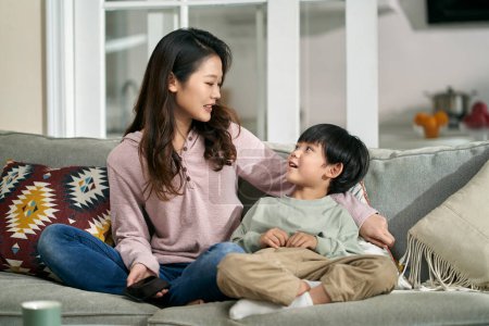 Foto de Joven asiático madre sentado en familia sofá en casa tener un agradable conversación con cinco años-od hijo - Imagen libre de derechos