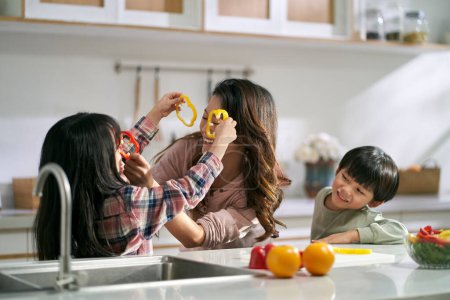 Photo for Young asian mother having fun with two children in family kitchen at home - Royalty Free Image
