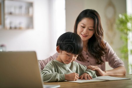Photo for Young asian mother sitting at table at home helping son with his study - Royalty Free Image