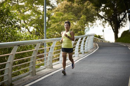 Photo for Young asian woman running jogging exercising outdoors in city park - Royalty Free Image