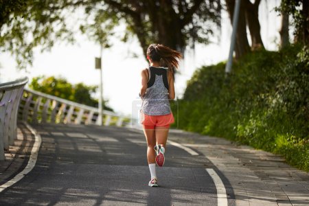 Téléchargez les photos : Vue arrière de jeune asiatique femme joggeuse exercice en plein air dans le parc de la ville - en image libre de droit