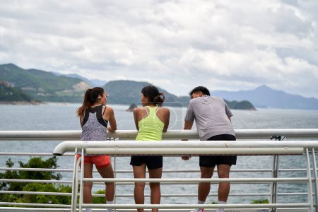 Foto de Vista trasera de los jóvenes asiáticos charlando relajante al aire libre por el mar - Imagen libre de derechos