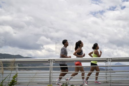 Téléchargez les photos : Trois jeunes asiatique adulte joggers exercice à l'extérieur dans parc par la mer - en image libre de droit
